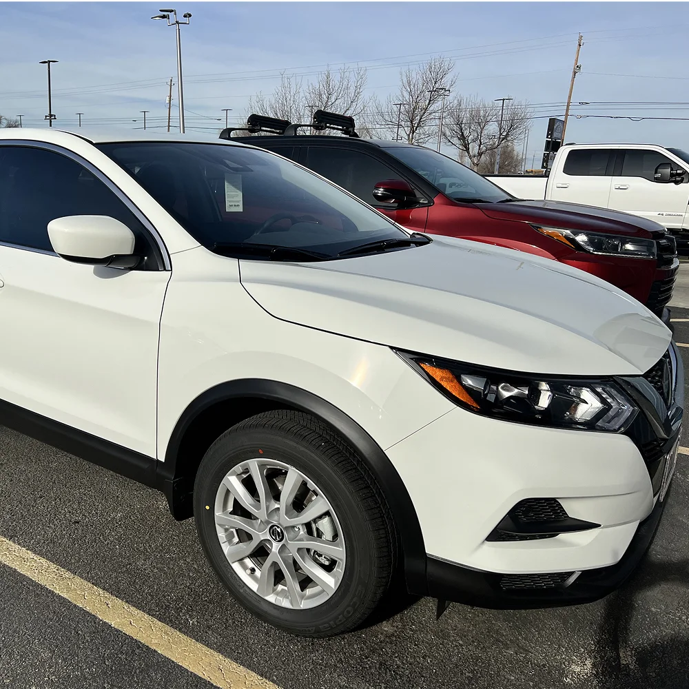 White compact SUV with clean black trim and silver wheels parked in a lot on a sunny day, with other vehicles including a red SUV and white pickup truck in the background.